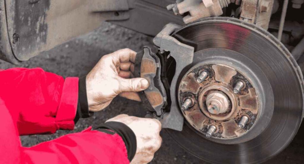 mechanic inspecting brake pads through the wheel